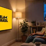 Mulher negra assistindo ao streaming Tela Brasil em TV na sala sentada no sofá