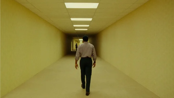 O ator Chiwetel Ejiofor anda em um corredor em cena em tom amarelo do filme Backrooms - Um Não-Lugar de 2026