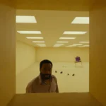 O ator Chiwetel Ejiofor anda em um corredor em cena em tom amarelo do filme Backrooms - Um Não-Lugar de 2026
