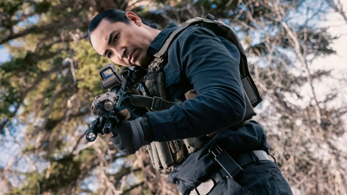 Personagem de Marshals Uma História de Yellowstone aponta um rifle para alguém que não aparece na imagem