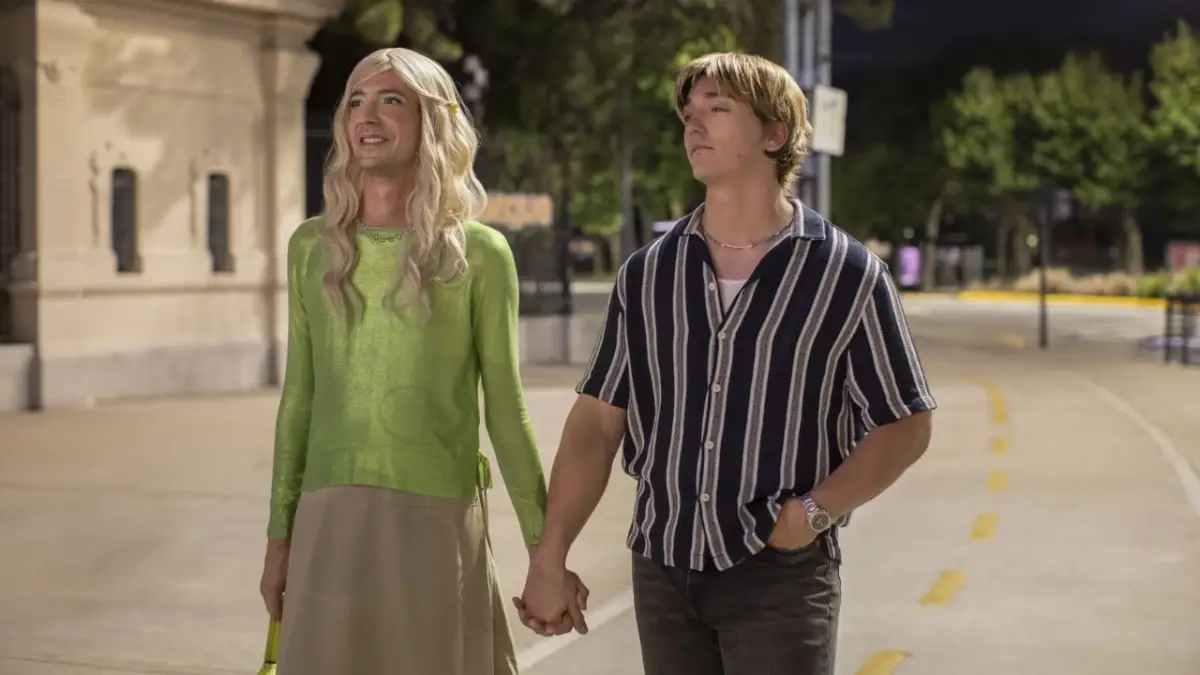 Protagonista da série da Caríssima da Netflix de mãos dadas com o namorado na rua usando uma blusa verde e uma saia bege (1)