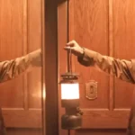 homem levanta luminária em cena do filme Hokum O Pesadelo da Bruxa de 2026 (1)