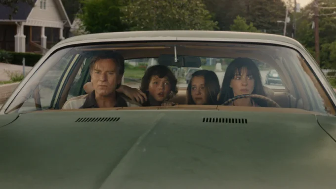 Anne Hathaway, Ewan McGregor, Maisy Stella e Christian Convery dentro de um carro em cena do filme O Fim da Rua, de 2026